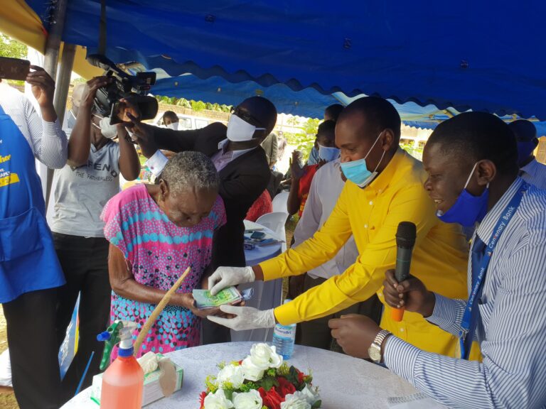 Gender Minister, Frank Tumwebaze handing over cash (Shs150,000) to a SAGE beneficiary during the launch in Lira town on Thursday