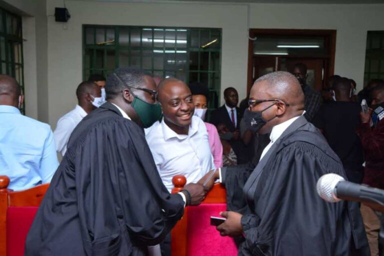 Hamis Kiggundu (in white) intercating with his lawyers