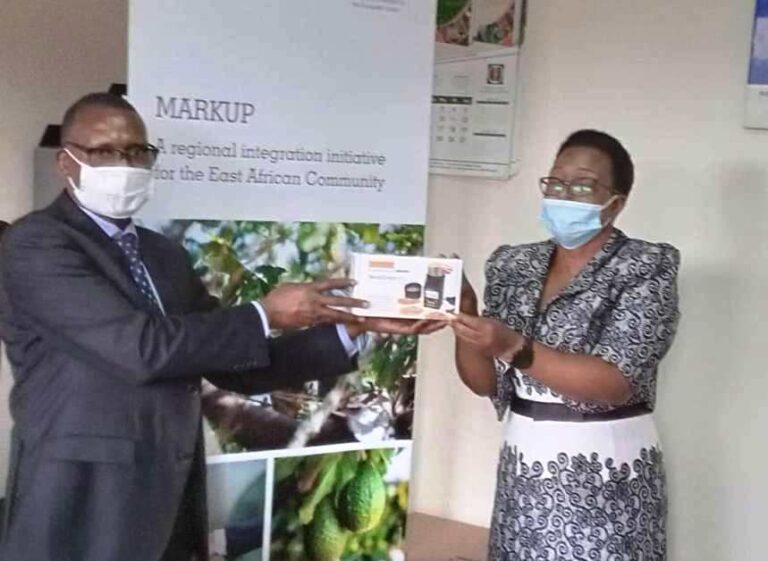 A farmer receives draminksi moisture metre from UCDA boss Emmanuel Iyamulemye (L)
