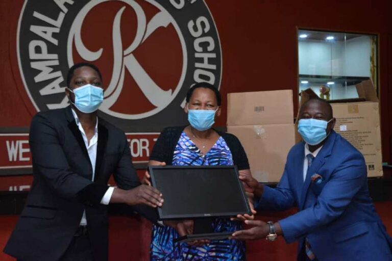 Sserwanja (R) receiving computers from Ruparelia Foundation officials