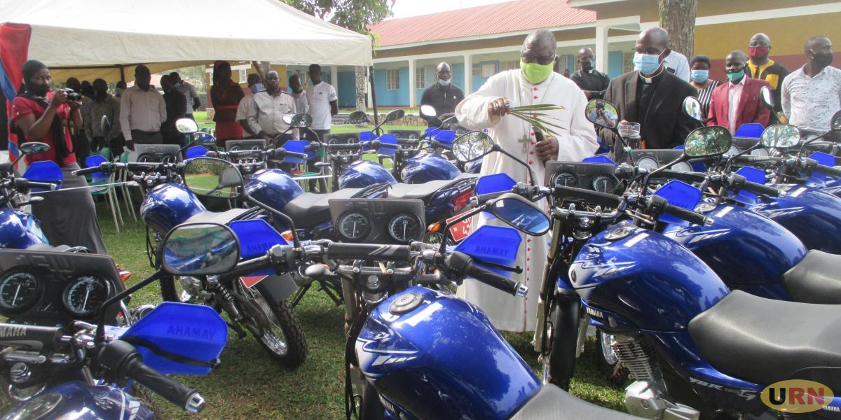 Bishop Paul Ssemogerere blesses the 18 motorcycles to be used in Global Climate project, following him is Fr. Hilary Muheezangango