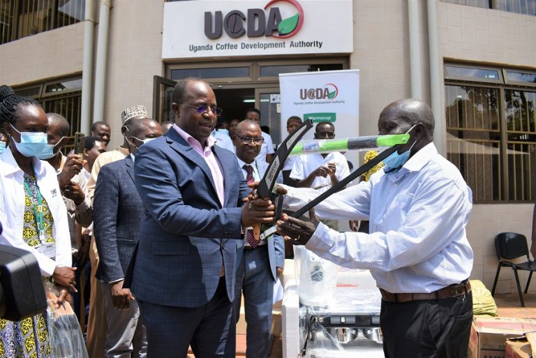 Minister Bwino (Left) handing over prunning saws and bow saws to a farmer