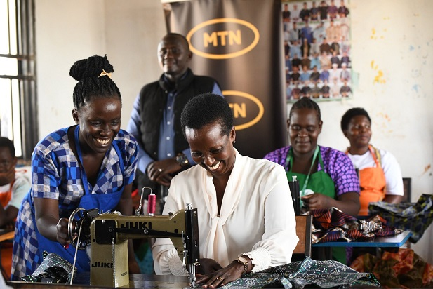 Allen Kagina, Trustee at MTN Foundation tries to saw clothes at Migeera Women Cente of Infleunce in Nakasongola District.