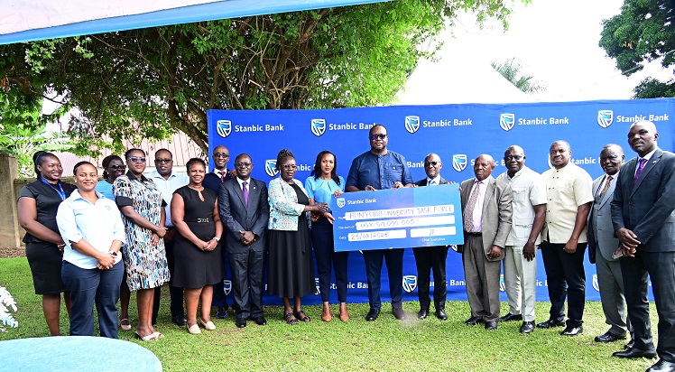 Stanbic Bank Uganda delegation led by Mumba Kalifungwa, the Chief Executive handing over a dummy cheque to the Bunyoro University task force and the area local leaders in Hoima City